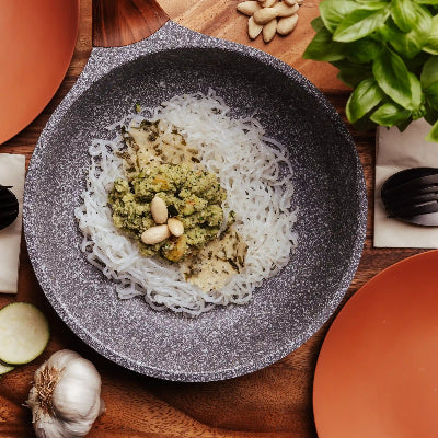 In einer Pfanne ist ein selbstgemachtes Zucchin Pesto den Konjak Spaghetti 5kcal Nudeln angerichtet. Der Tisch rundherum ist gedeckt